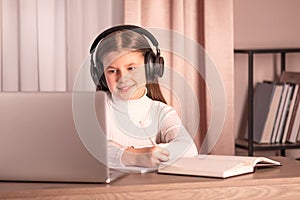 Teenager wearing headphones using laptop to watch online seminar. E-learning concept. Distance education