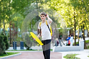 Teenager in white t-shirt spends free time training skating in the city park. Practicing skills freestyle  making tricks.