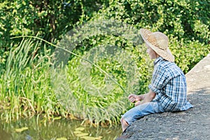 Teenager with wooden rustic fishing rod angling on concrete bridge photo