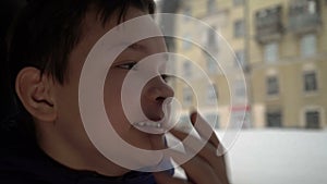 Teenager yawns and looks out the car window in winter