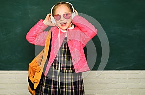 Teenager younf school girl with backpack on blackboard. Portrait of a teen female student. Funny school girl wearing