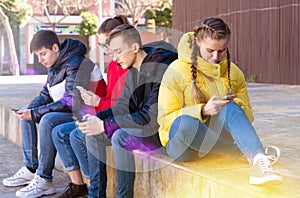 Teenagers absorbed in phones outdoors