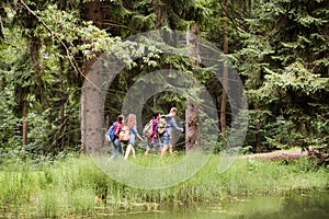 Teenagers with backpacks hiking in forest. Summer vacation.