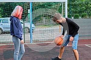 Teenagers boy and girl playing street basketball together