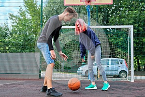 Teenagers boy and girl playing street basketball together