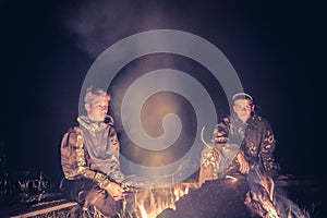 Teenagers boys in the camp by the fire in the night