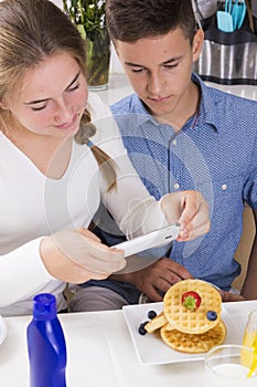 Teenagers decorating pancakes with berry