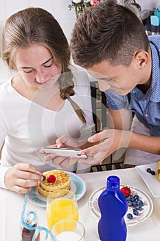 Teenagers decorating pancakes with berry