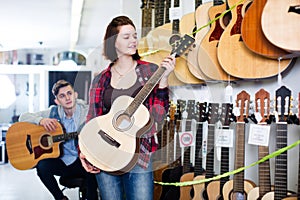 Teenagers examining guitars in shop