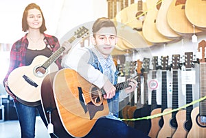 Teenagers examining guitars in shop