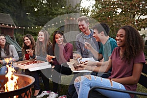 Teenagers at a fire pit eating take-away pizzas, close up