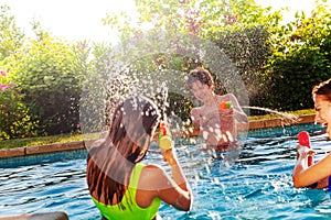 Teenagers friends play with water-gun in pool