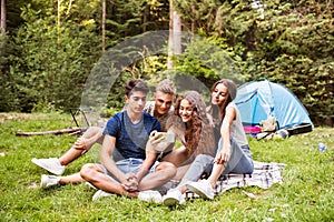 Teenagers in front of tent camping in forest.