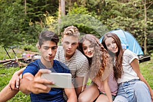 Teenagers in front of tent camping in forest.