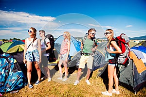 Teenagers in front of tents with backpacks, summer festival