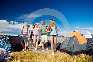 Teenagers in front of tents with backpacks, summer festival