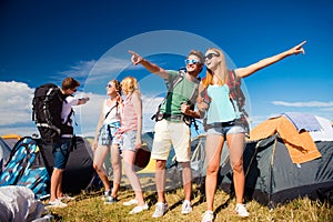 Teenagers in front of tents with backpacks, summer festival
