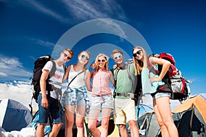 Teenagers in front of tents with backpacks, summer festival