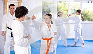 Teenagers girl and boy in kimono sparring together in gym during karate training