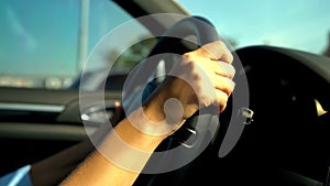 Teenagers hands holding black steering wheel, girl driving car uncertainly