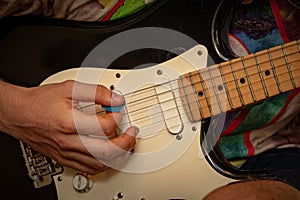 Teenagers hands playing an electric base guitar with a pick