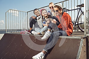 Teenagers having fun with smartphone in skateboard park