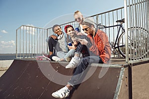 Teenagers having fun with smartphone in skateboard park