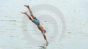 Teenagers jump into the water and swim in the lake on a hot summer day. Active recreation on an open pond. Children jump into the