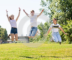 Teenagers jumping on green lawn in summertime