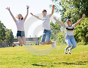 Teenagers jumping on green lawn in summertime