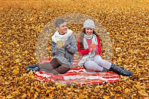 Teenagers laughing loudly talking flirt on a picnic on the plaid in the park