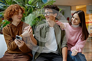 Teenagers listening music via mobile phone during pastime in shopping mall