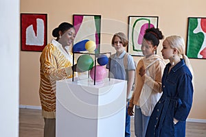 Teenagers listening to teacher or tour guide in modern art gallery