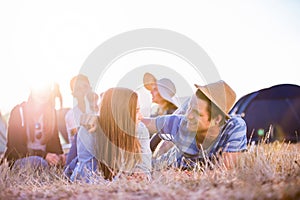 Teenagers lying on the ground in front of tents