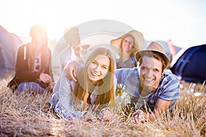 Teenagers lying on the ground in front of tents