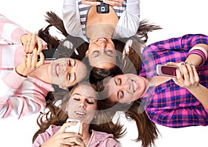 Teenagers lying on white with cellphones smiling