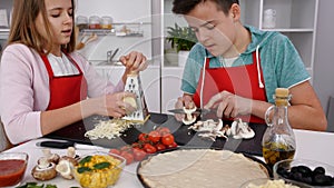 Teenagers making pizza in the kitchen at home