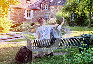 Teenagers people and travel concept. Teens  sitting on the bench and making photos in the street of an old town, Rochefort-en-