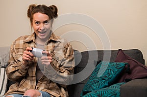 Teenagers play video games. Young girl with a gamepad in her hands sitting in a room on the sofa. Have fun playing adventure video