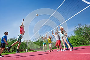 Teenagers play volleyball game on playing ground
