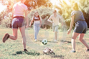 Teenagers playing football on green grass in summertime