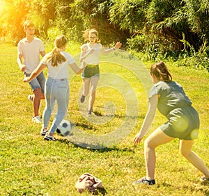 Teenagers playing football on green grass in summertime