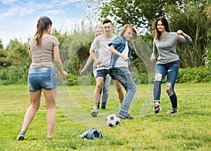 Teenagers playing football in park .