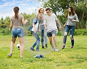 teenagers playing football in park .