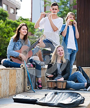 Teenagers playing music outdoors .