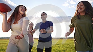 Teenagers playing rugby in the park. A group of teenagers play American football run outdoors in the park in summer