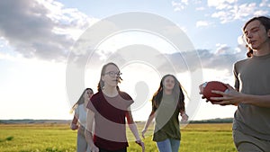 teenagers playing rugby in the park. a group of teenagers play american football run outdoors in the park in summer