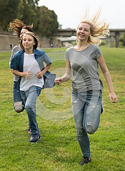 Teenagers running through green lawn in summer in park