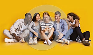 Teenagers sitting on floor and looking at smartphone screen