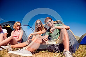 Teenagers sitting on the ground in front of tents